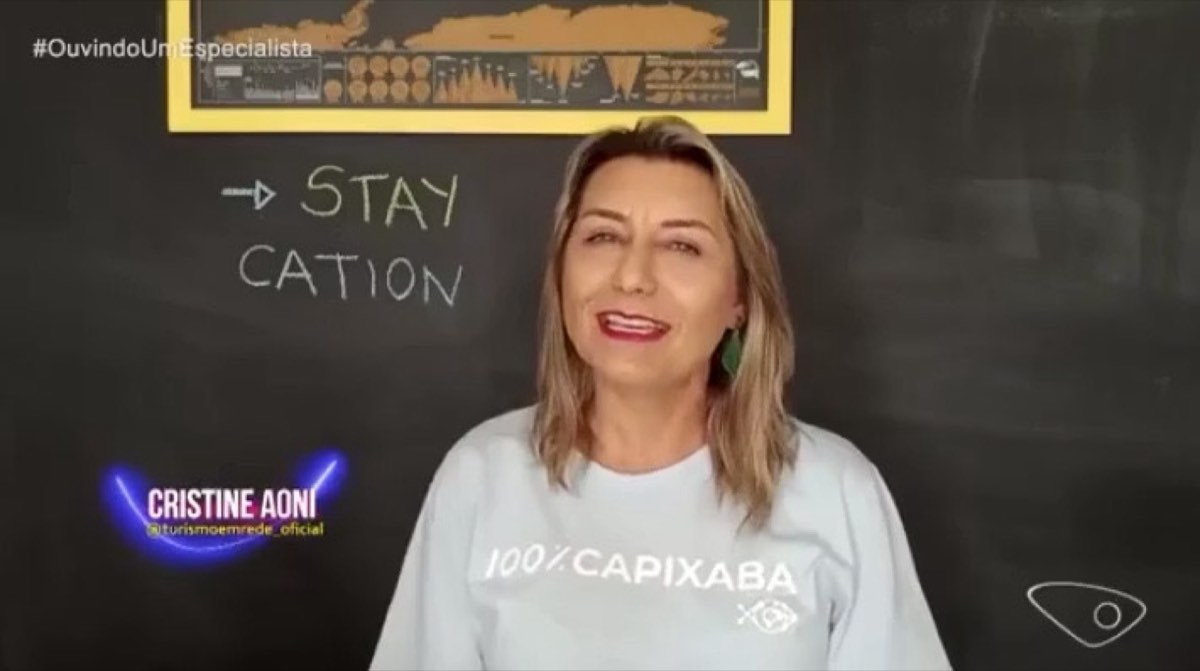 Cristine Aoni em frente a um quadro com a palavra staycation